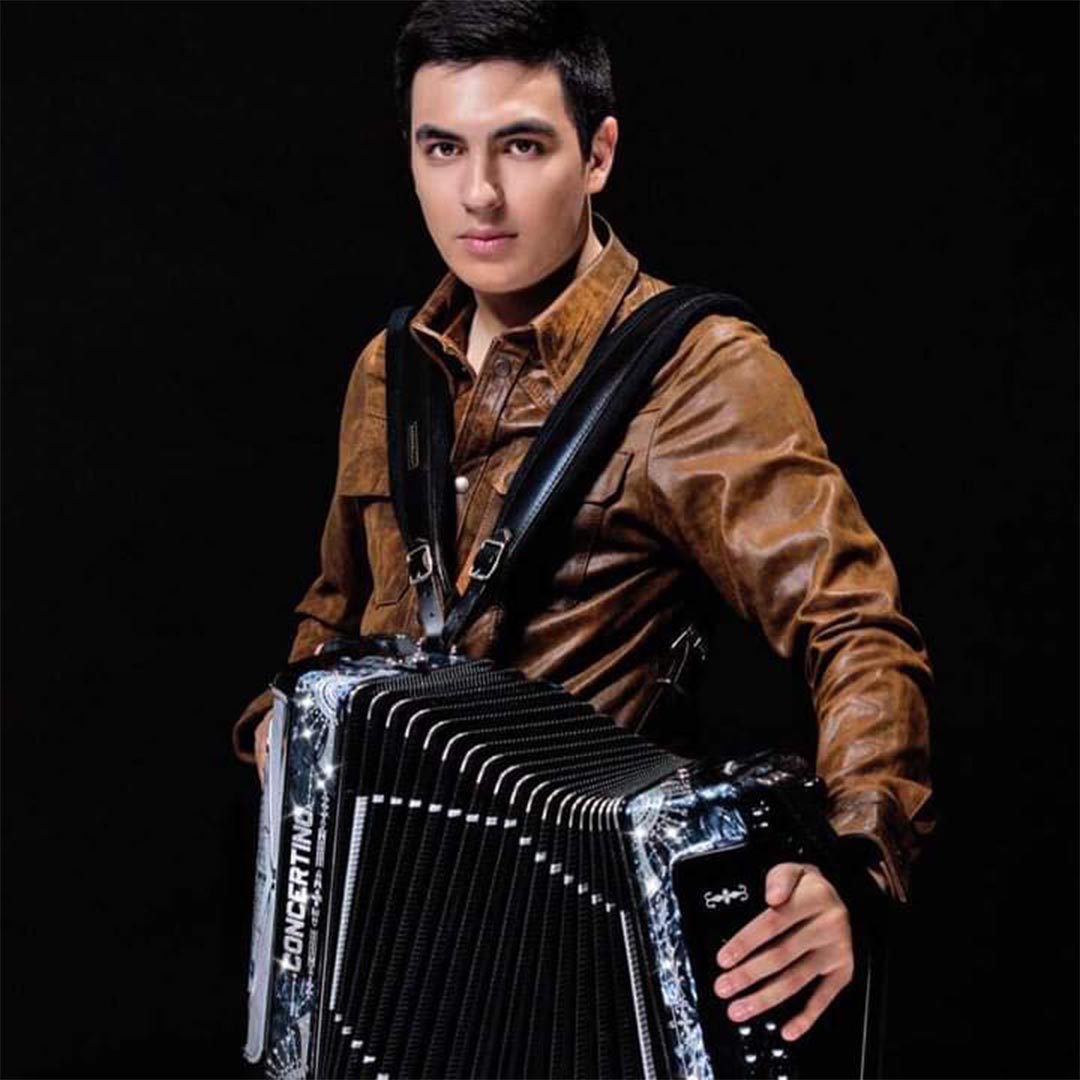 Raúl Hernández Jr con chamarra color camel y un acordeón. 